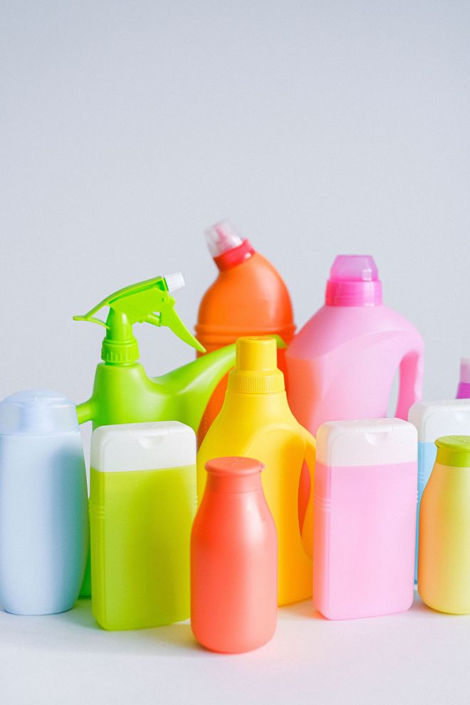 Assorted colorful plastic spray bottles and containers arranged on a light background