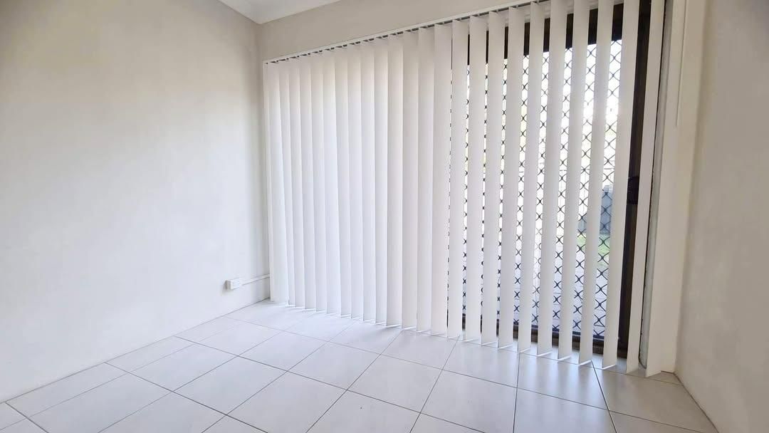 An Empty Room with A Sliding Glass Door and Vertical Blinds — Barry's Affordable Blinds in Taylors Beach, NSW