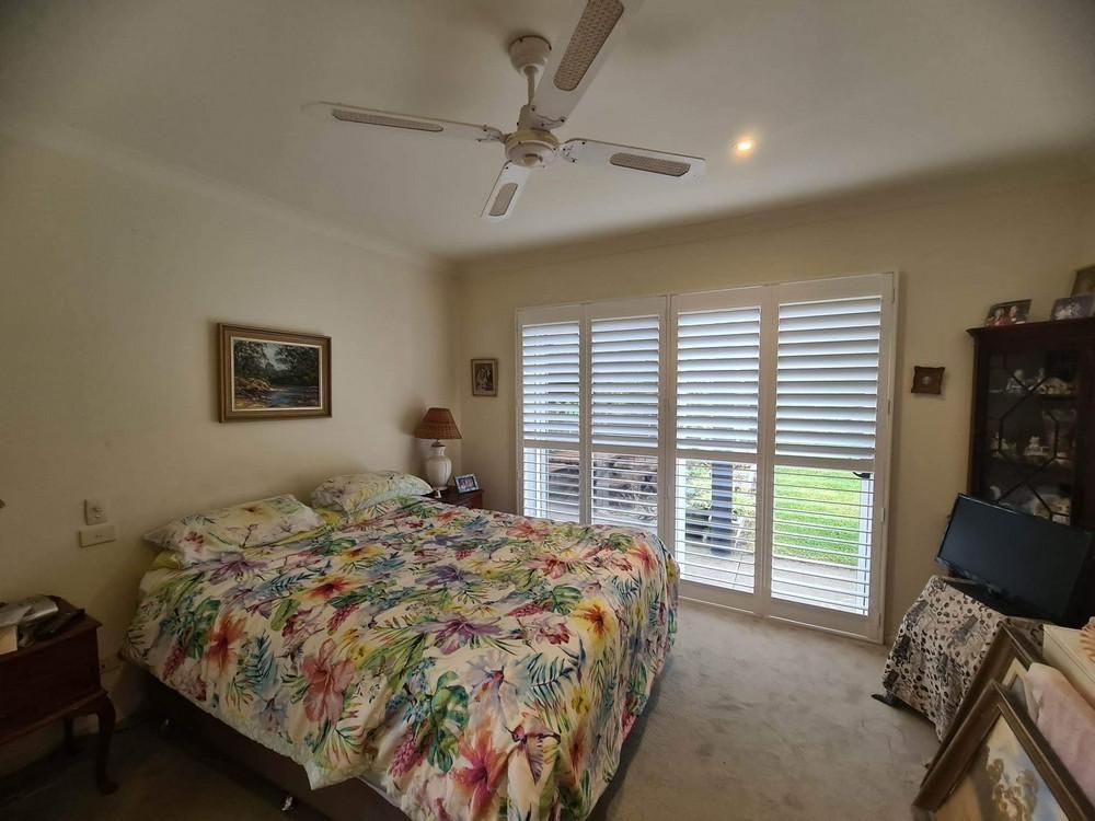 A Bedroom with A Large Bed and A Plantation Shutters — Barry's Affordable Blinds in Taylors Beach, NSW