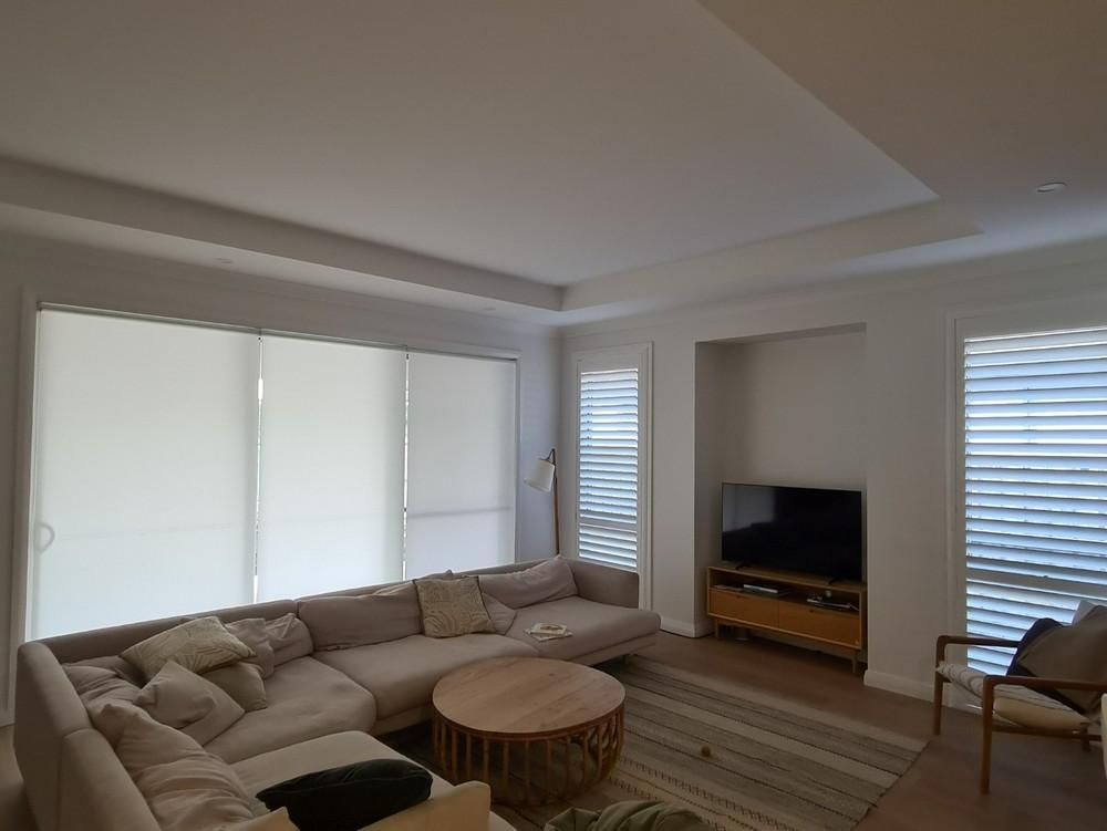A Living Room with Shutters, A Couch, Chair, Table and Television — Barry's Affordable Blinds in Taylors Beach, NSW