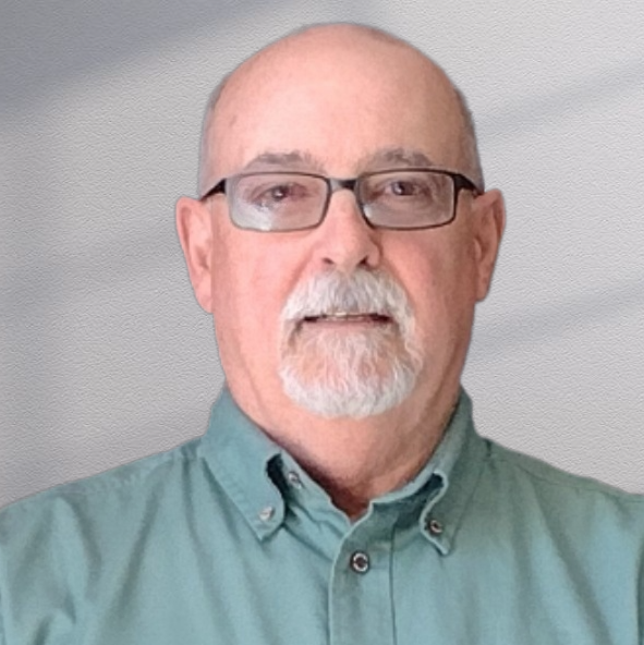 Man with glasses and goatee in a green shirt, looking at the camera with a neutral expression.