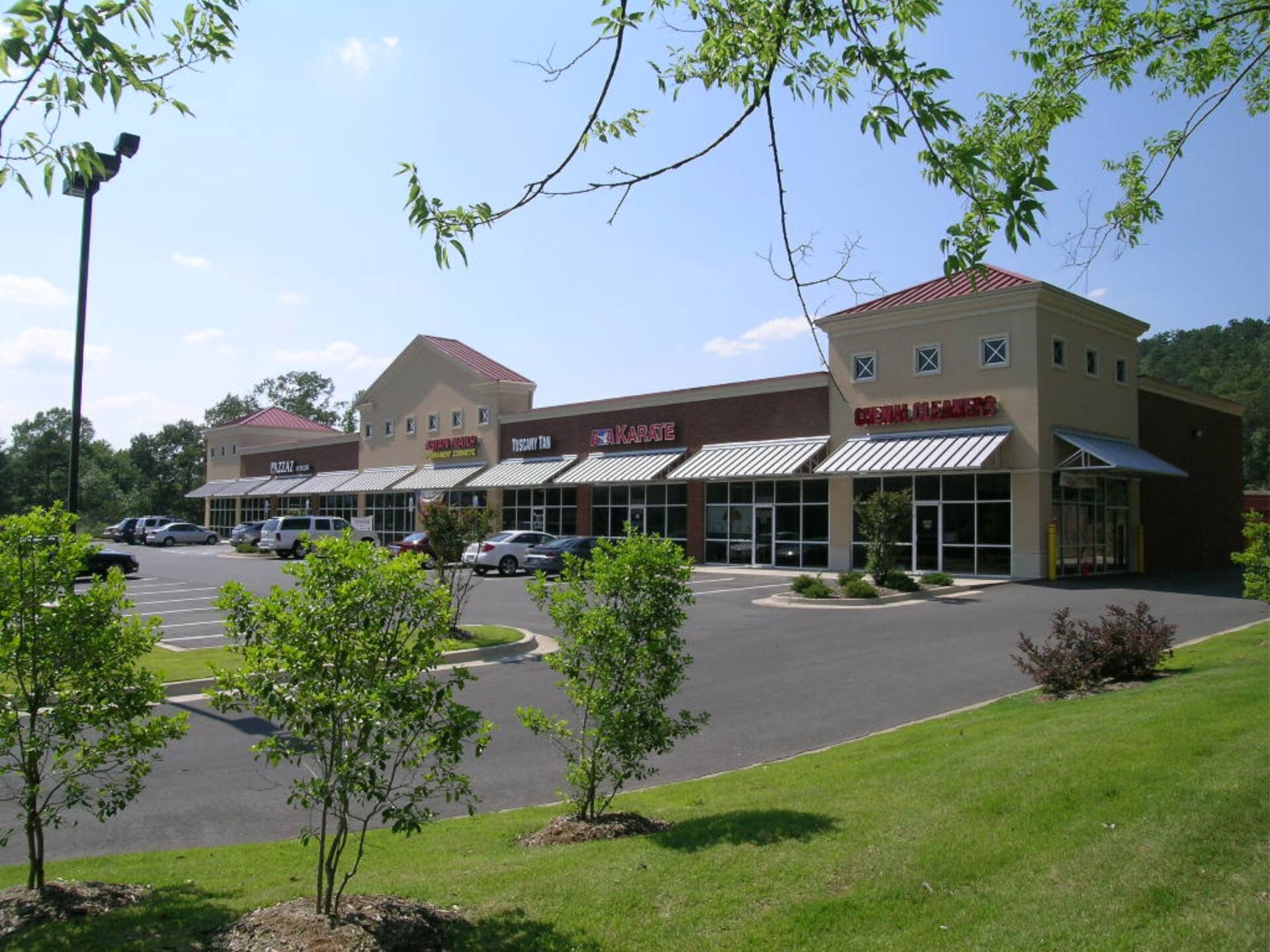 Strip mall with awnings and trees on a sunny day.