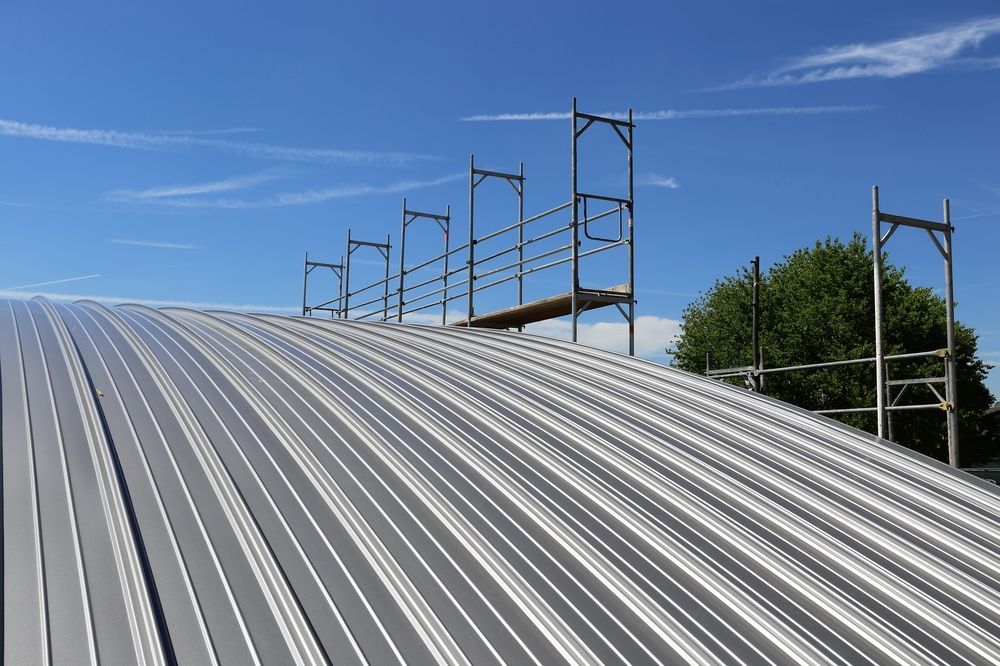 A metal roof with scaffolding on top of it and a blue sky in the background.