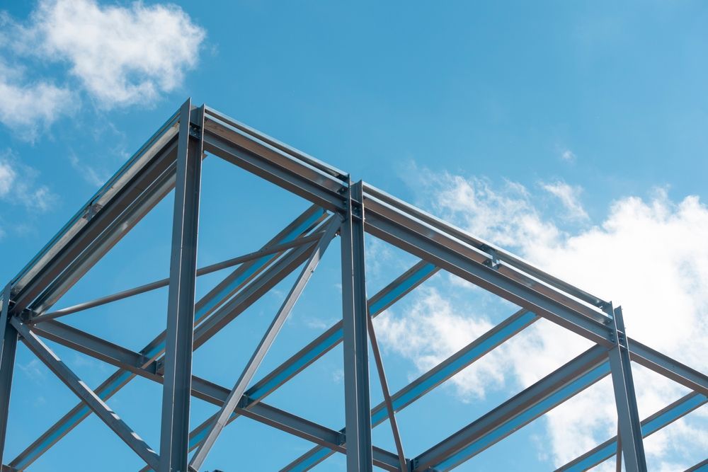 A metal structure is being built against a blue sky with clouds.