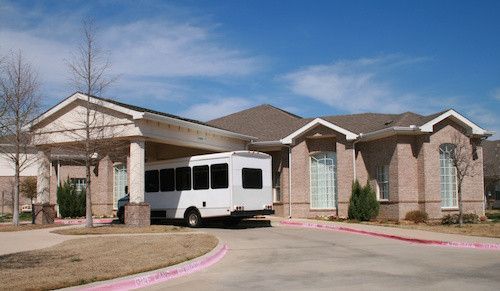 A white bus is parked in front of a large brick building.