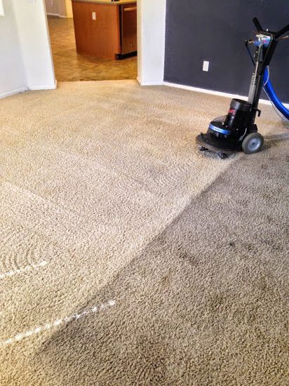 A vacuum cleaner is cleaning a carpet in a living room.