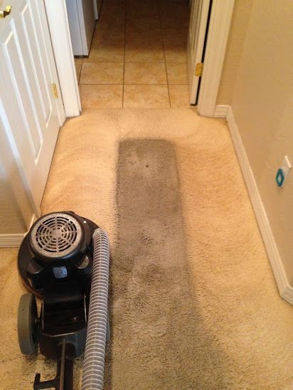 A vacuum cleaner is sitting on a carpet in a hallway.