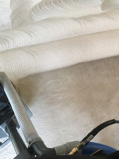 A vacuum cleaner is being used to clean a carpet.