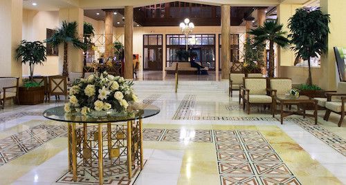 There is a table with flowers on it in the middle of the lobby.