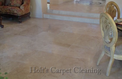 A living room with a couch and chairs and a tile floor.