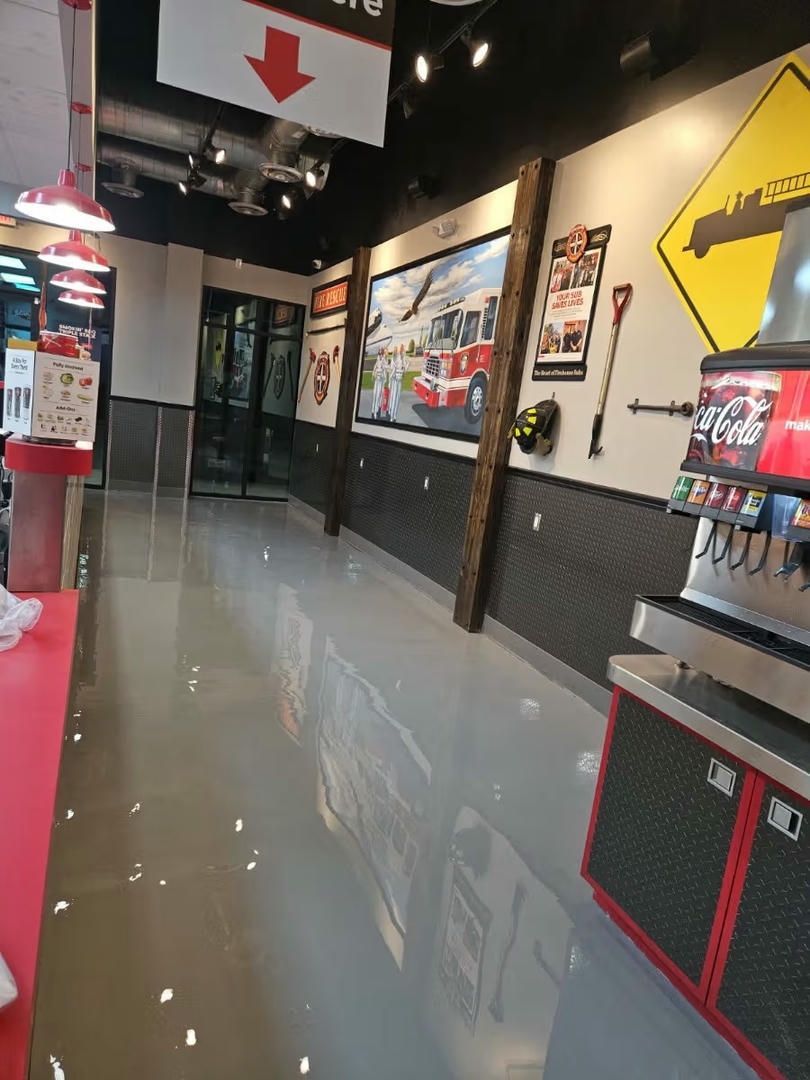 Interior shot of a store with glossy gray floor and black-tiled accent wall. Soda machine in the right corner.