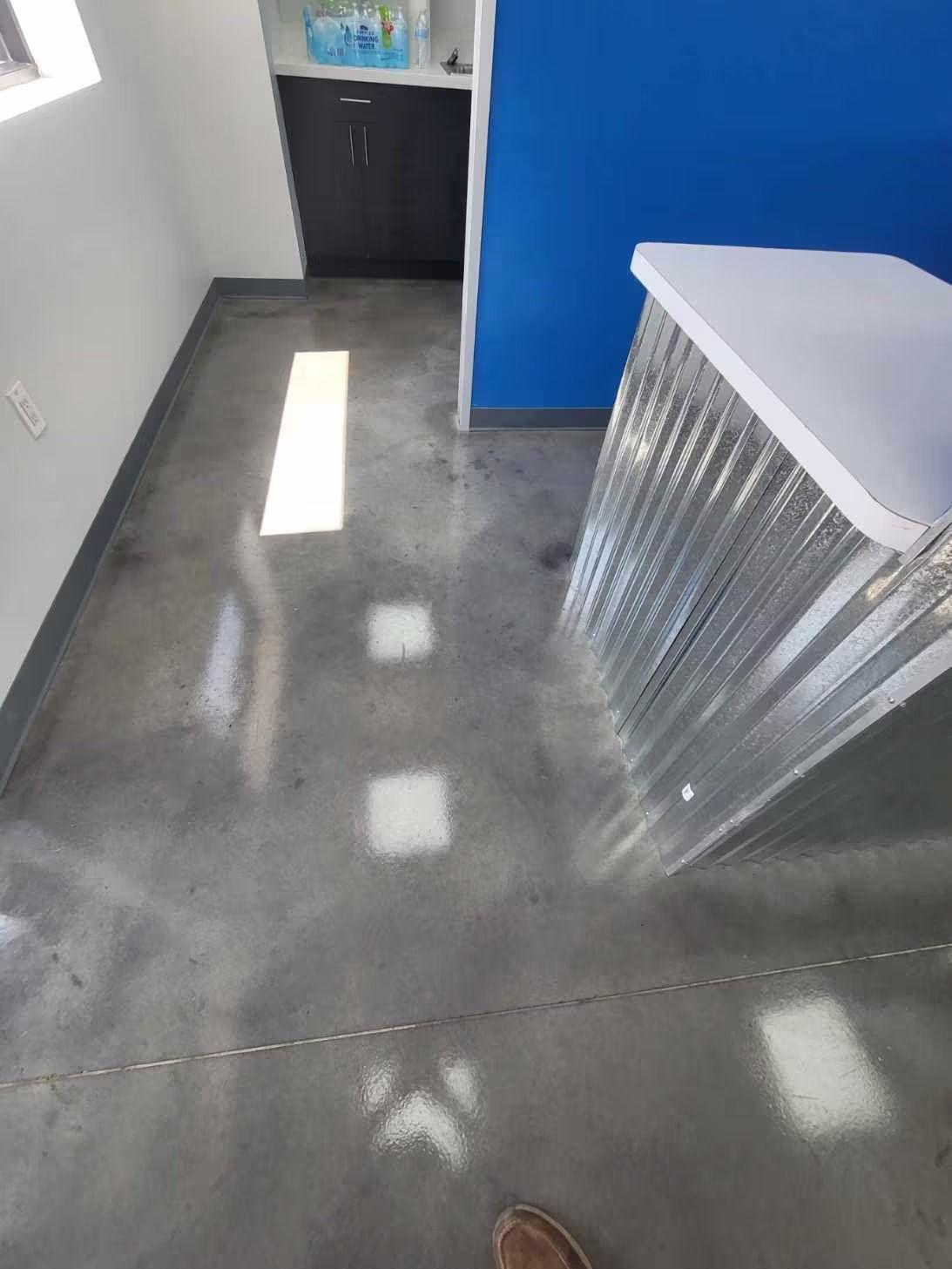 A room with polished concrete floor, blue wall, and white counter.