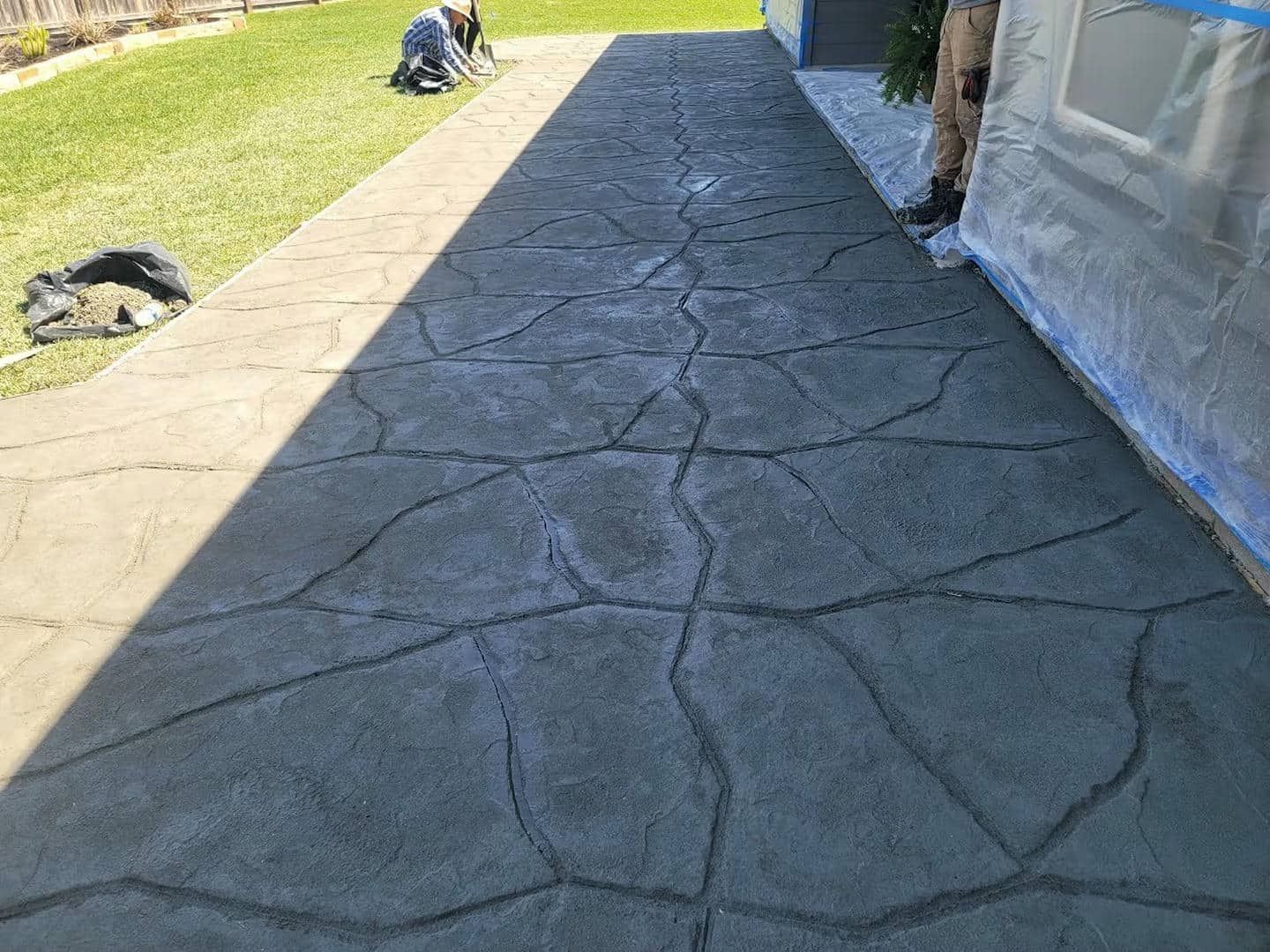 A concrete walkway with a cracked stone pattern, fresh concrete work in progress.