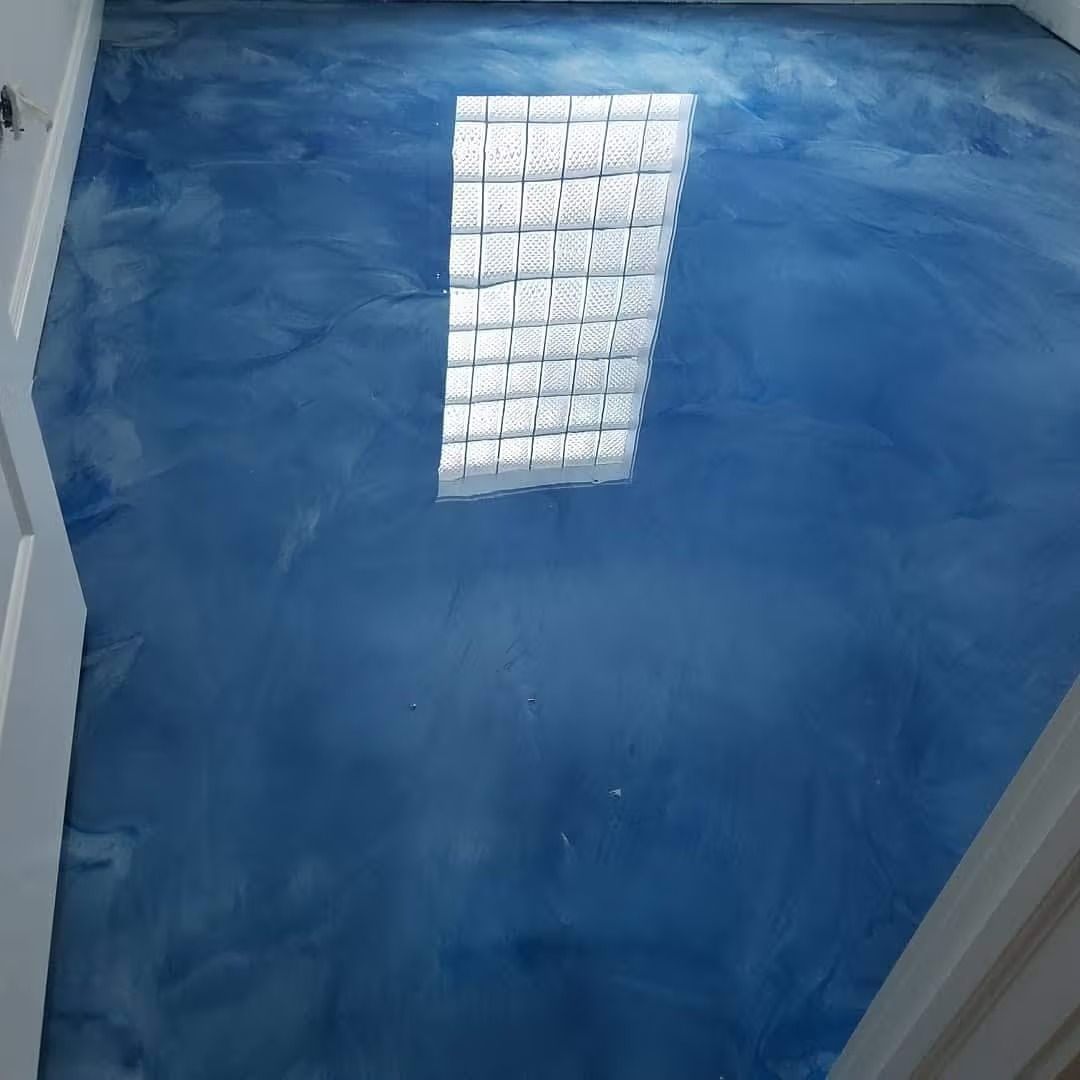 Blue metallic epoxy floor reflecting a light source above.