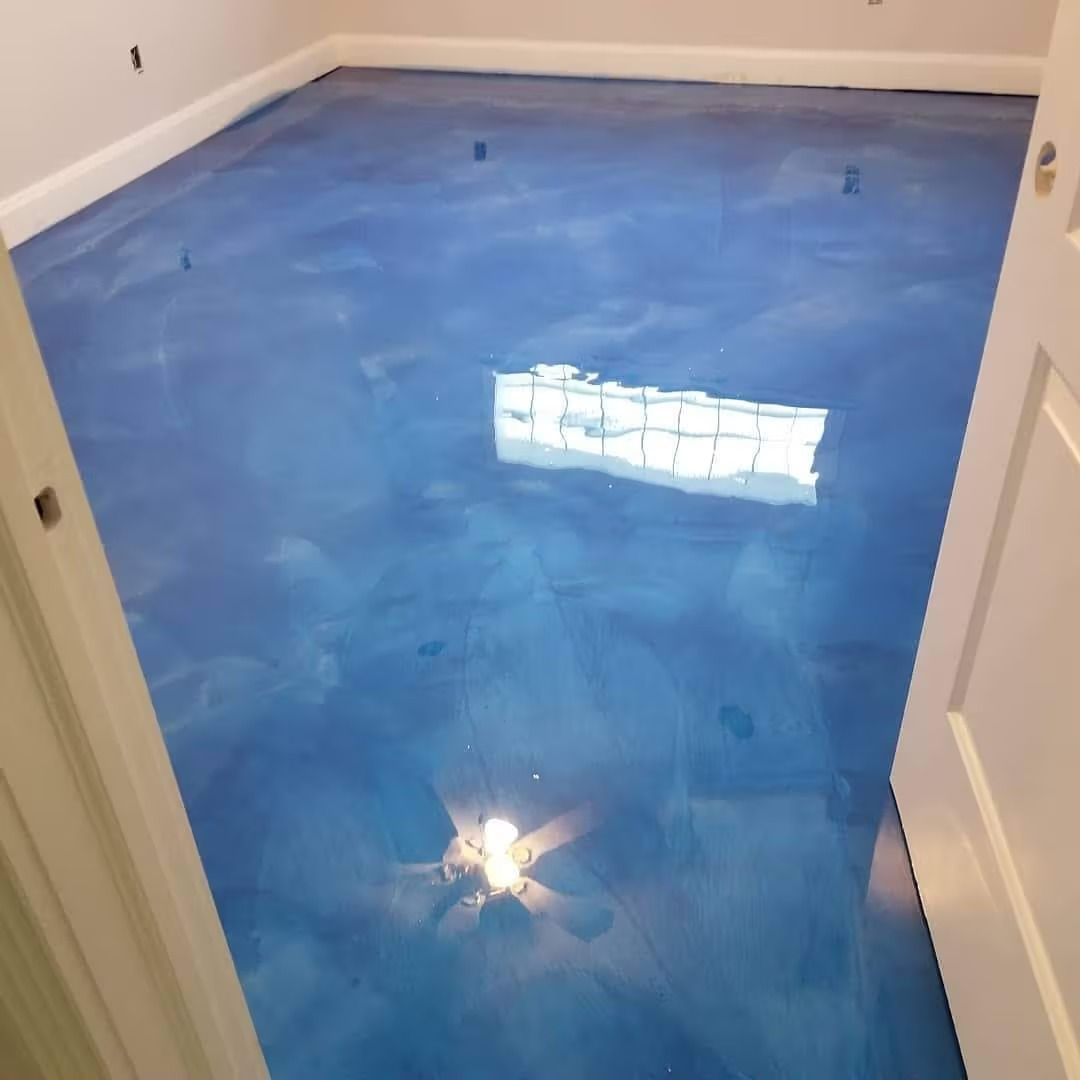 Blue epoxy flooring reflecting light in a room with white trim and a partially open door.