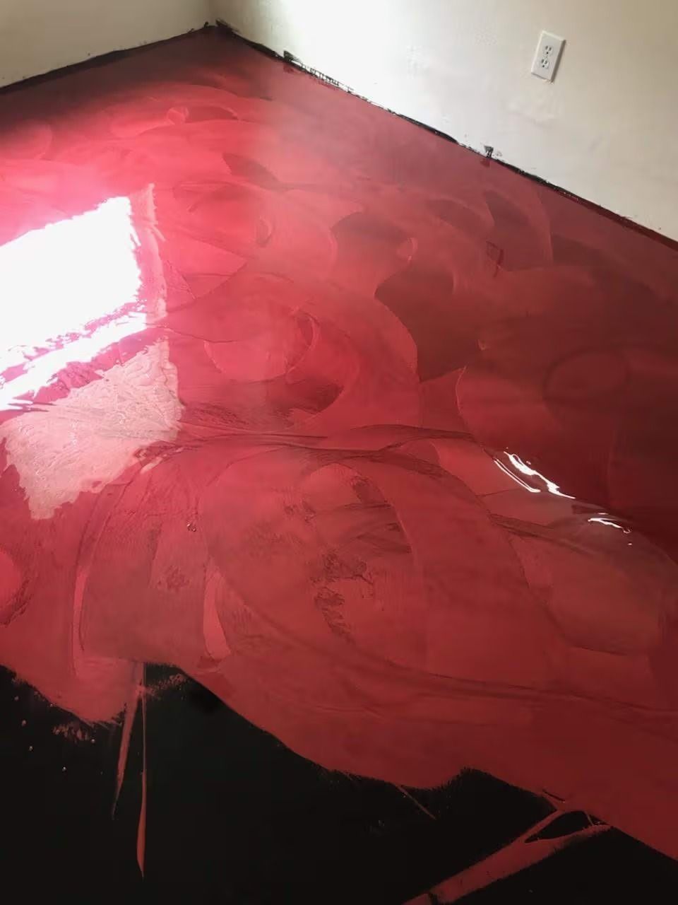 Red and black epoxy flooring with light reflections.