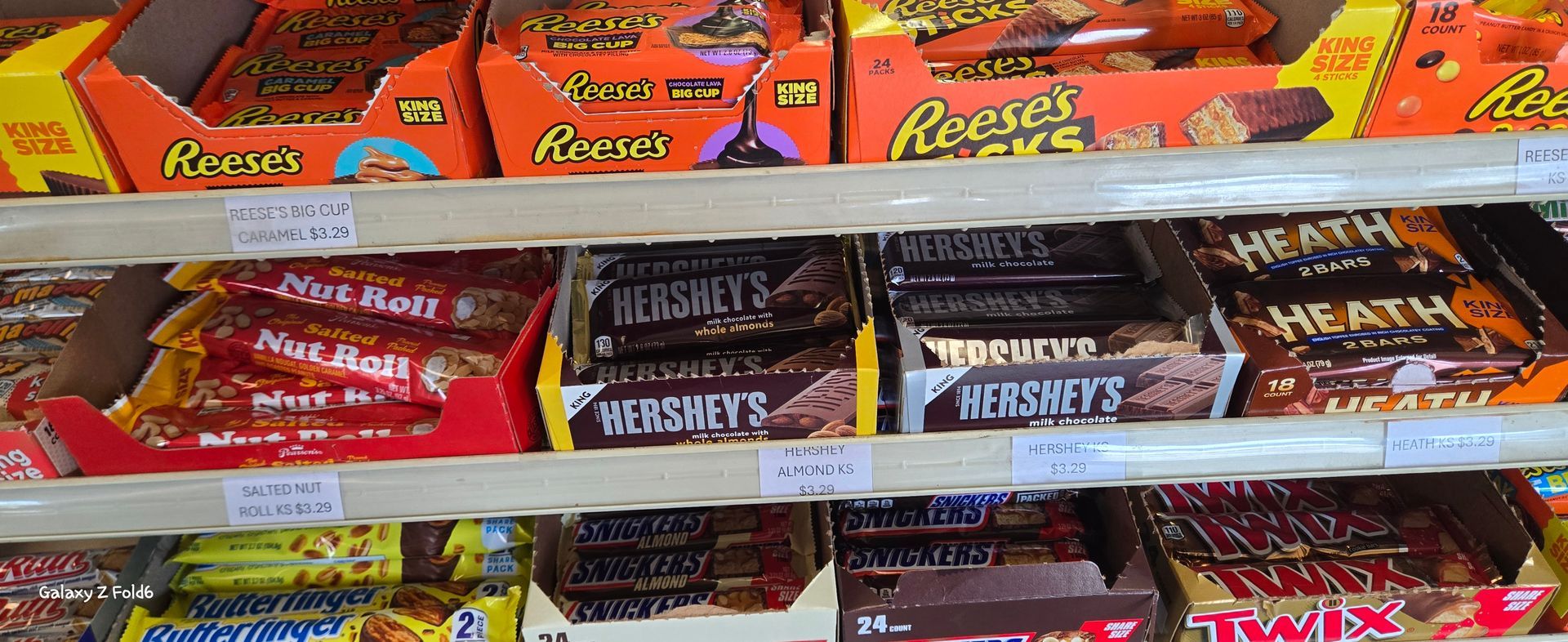 A shelf full of candy bars including reese 's and hershey 's
