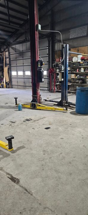 A man is working on the underside of a car in a garage.