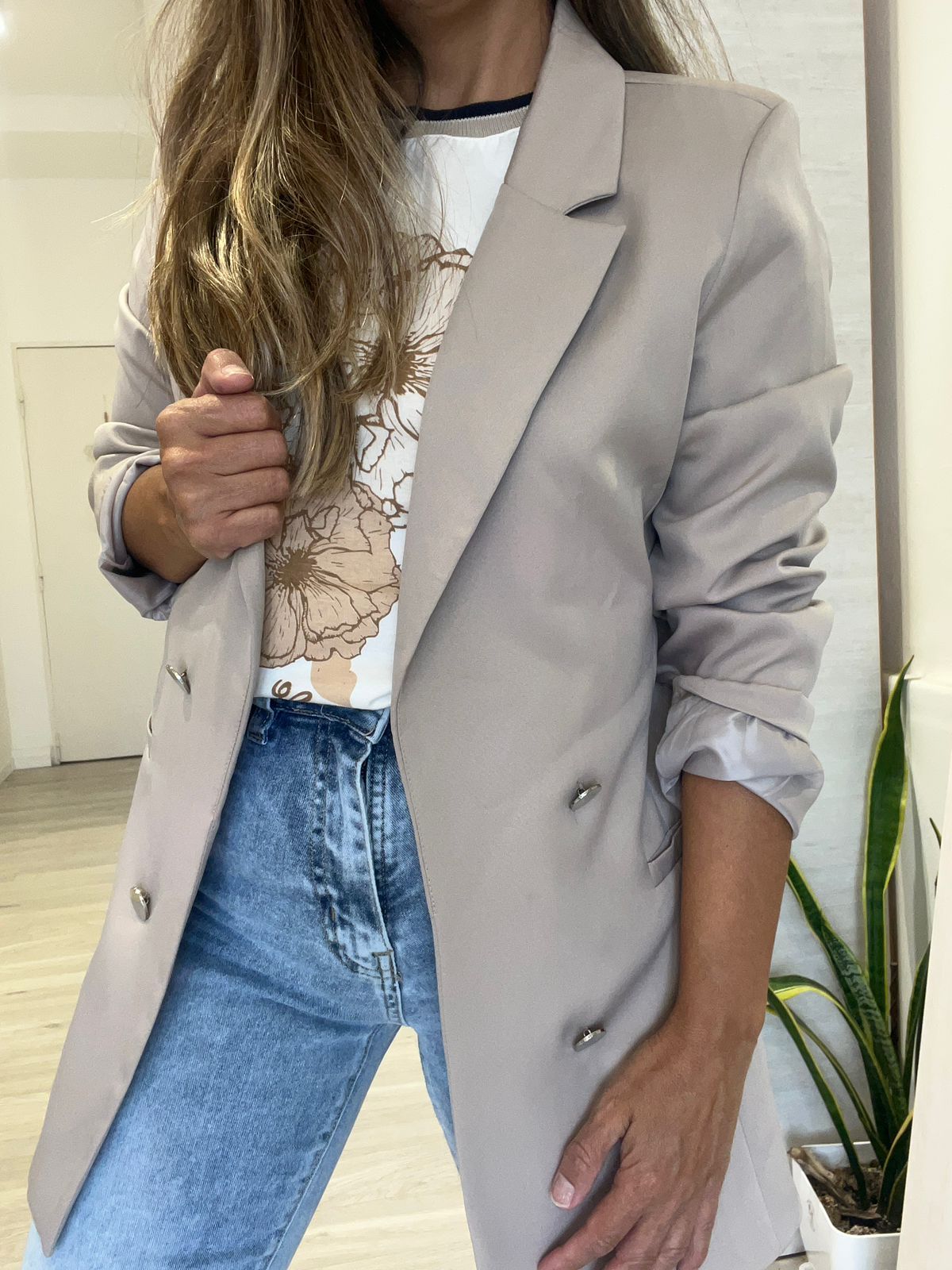 Una mujer lleva un blazer y jeans.