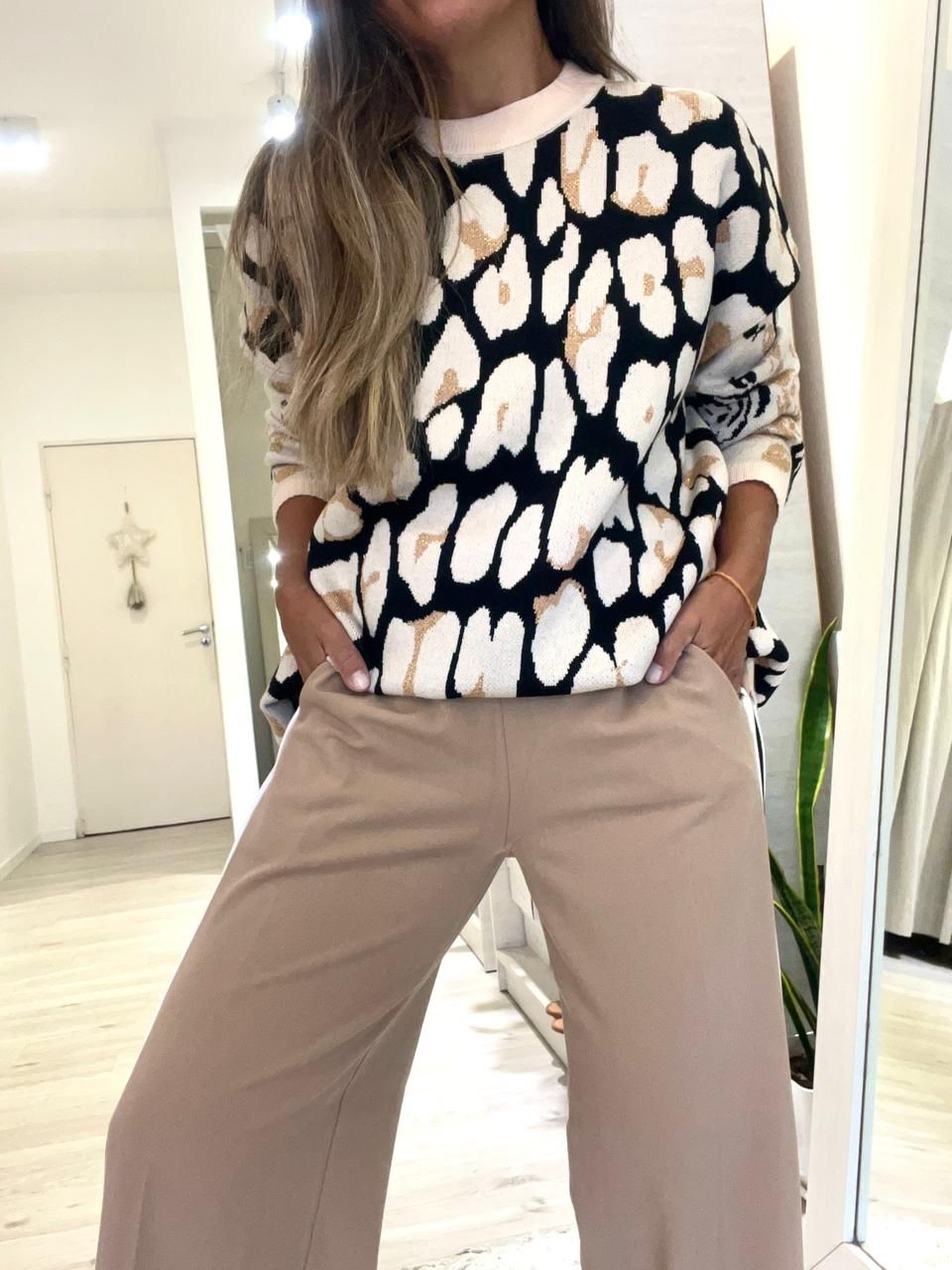 Una mujer que lleva un suéter con estampado de leopardo y pantalones anchos.