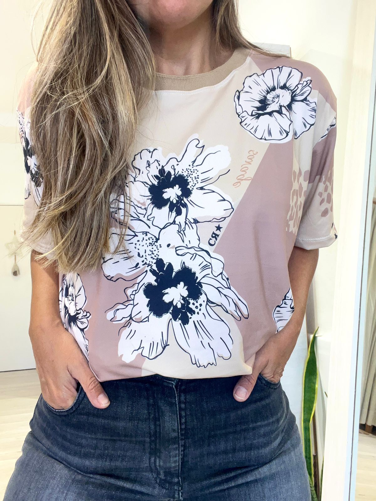 Una mujer lleva una camiseta floral y jeans.
