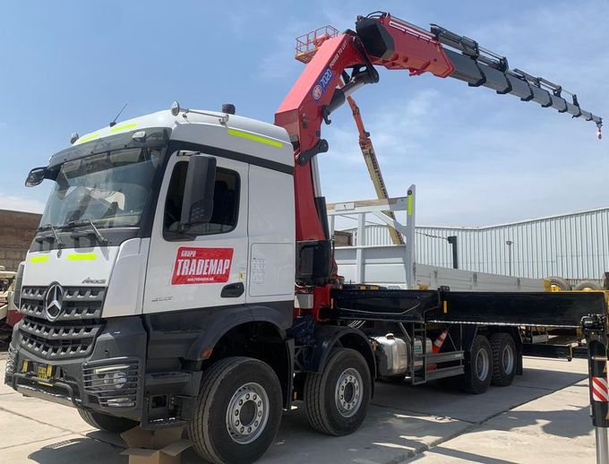 Un camión de servicio blanco con una alta grúa hidráulica amarilla montada en la plataforma
