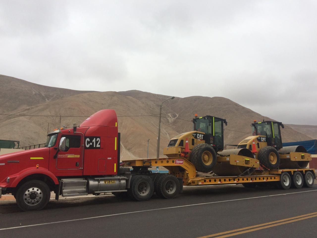 Una gran grúa móvil blanca se alza en un patio industrial, levantando una carga pesada
