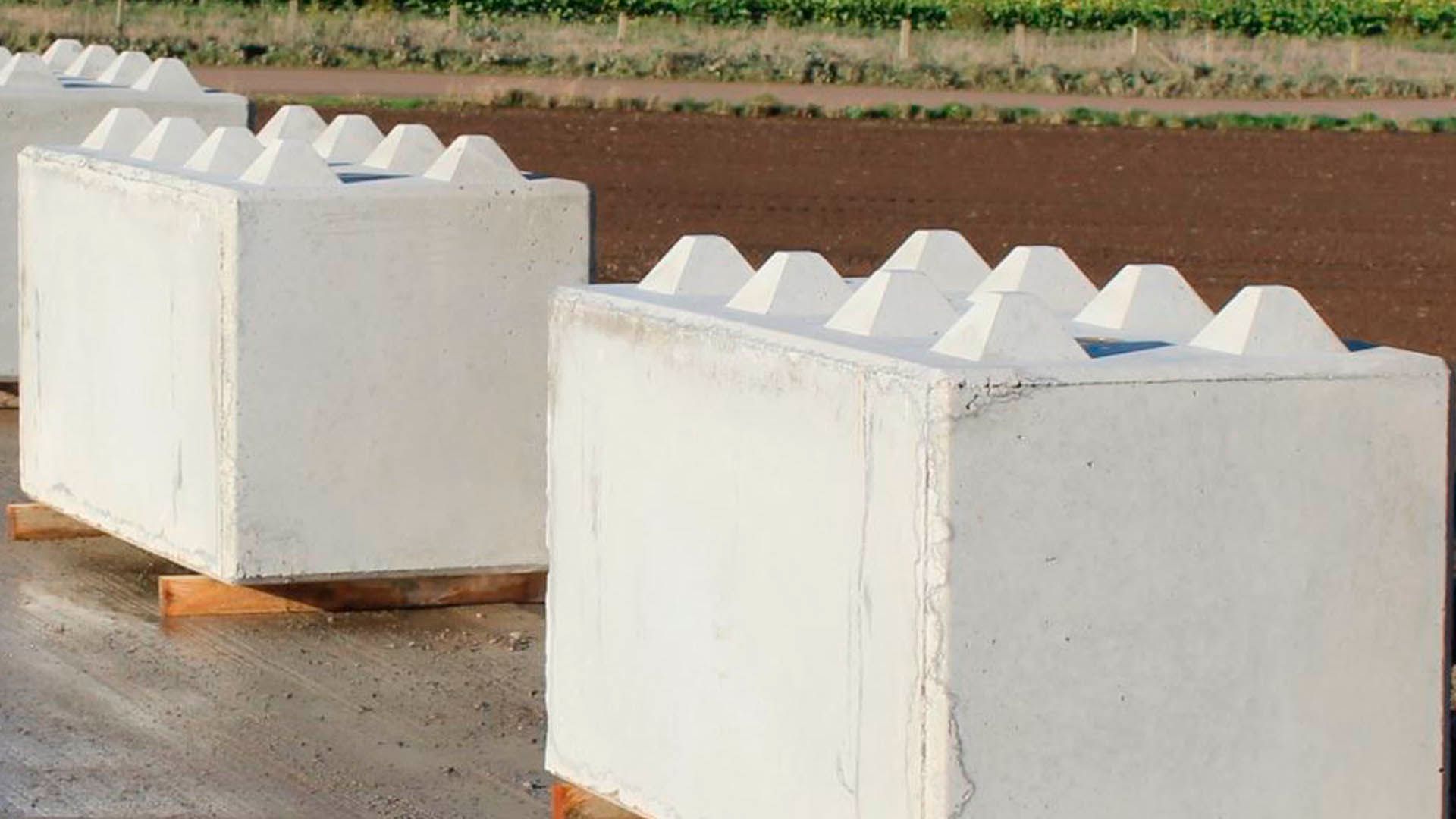 Large white rectangular concrete blocks with interlocking top studs sit on wooden supports outdoors.