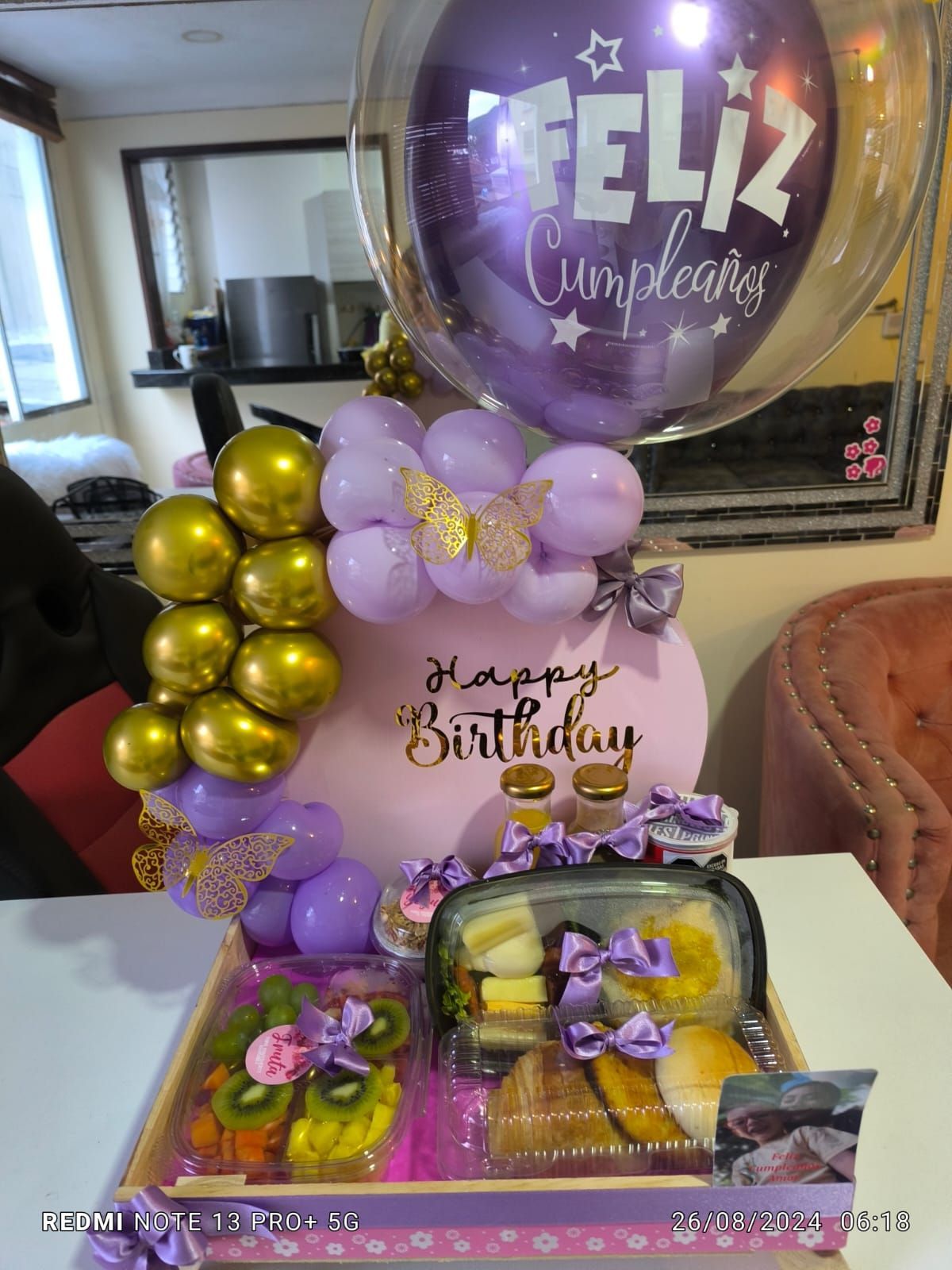 Arreglo de cumpleaños con globos, bandeja de comida, fruta, cupcakes y las palabras