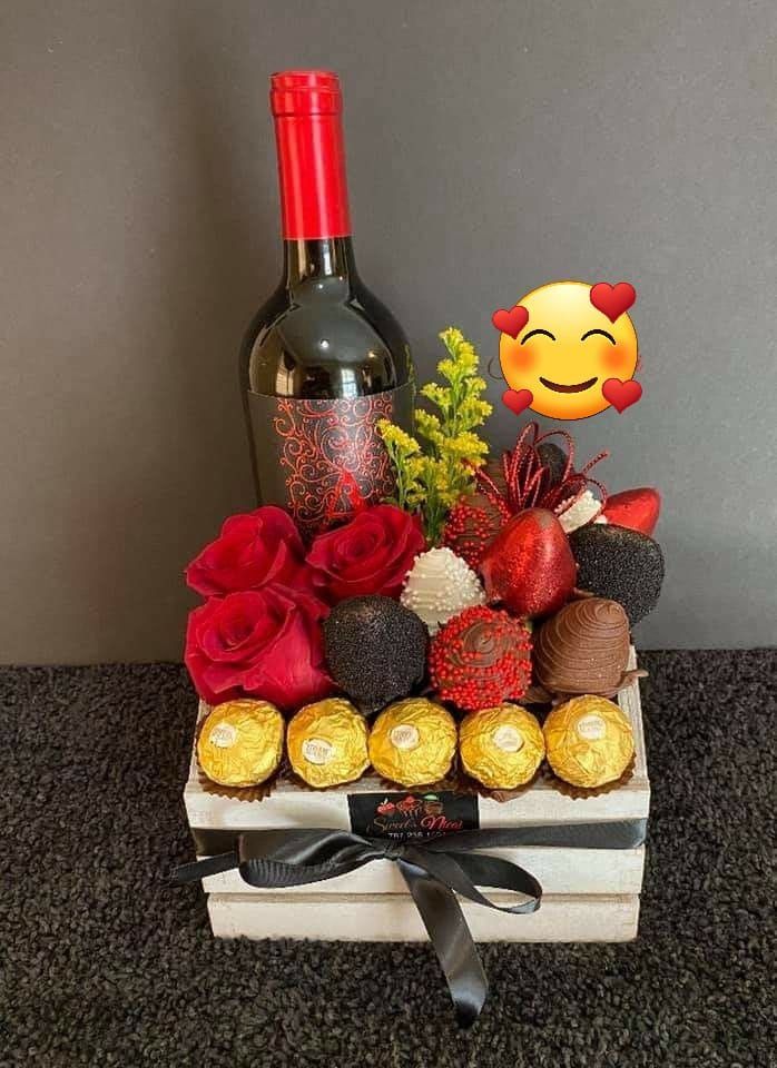 Caja de regalo con rosas rojas, bombones, vino y emojis.