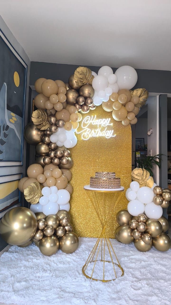 Arco de globos dorados y blancos con cartel de