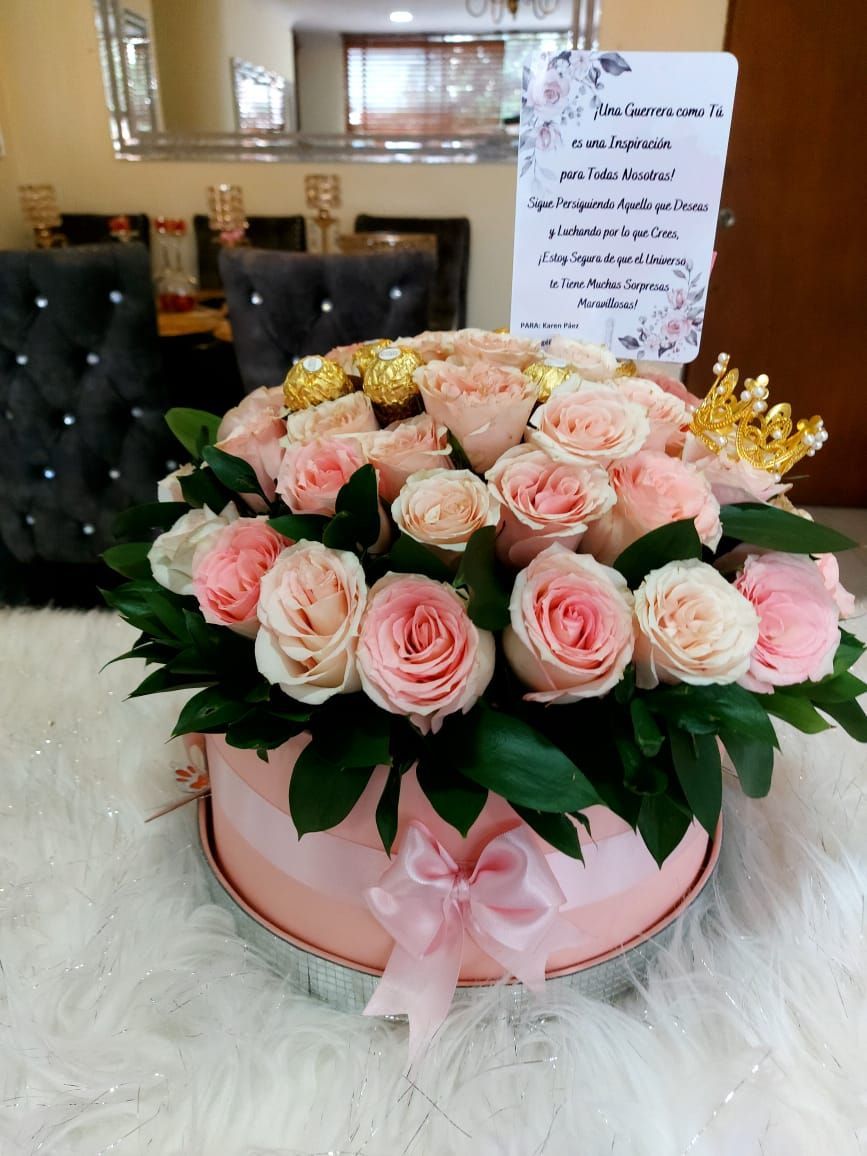 Rosas rosas y bombones en una caja redonda rosa con un lazo, una tarjeta y una corona dorada.