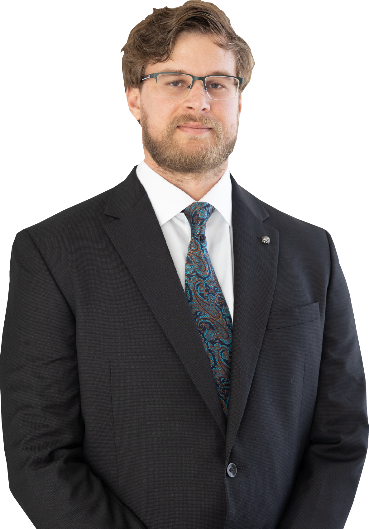 A professional headshot of a person with a beard, wearing a dark suit, white shirt, and patterned tie against a white background.