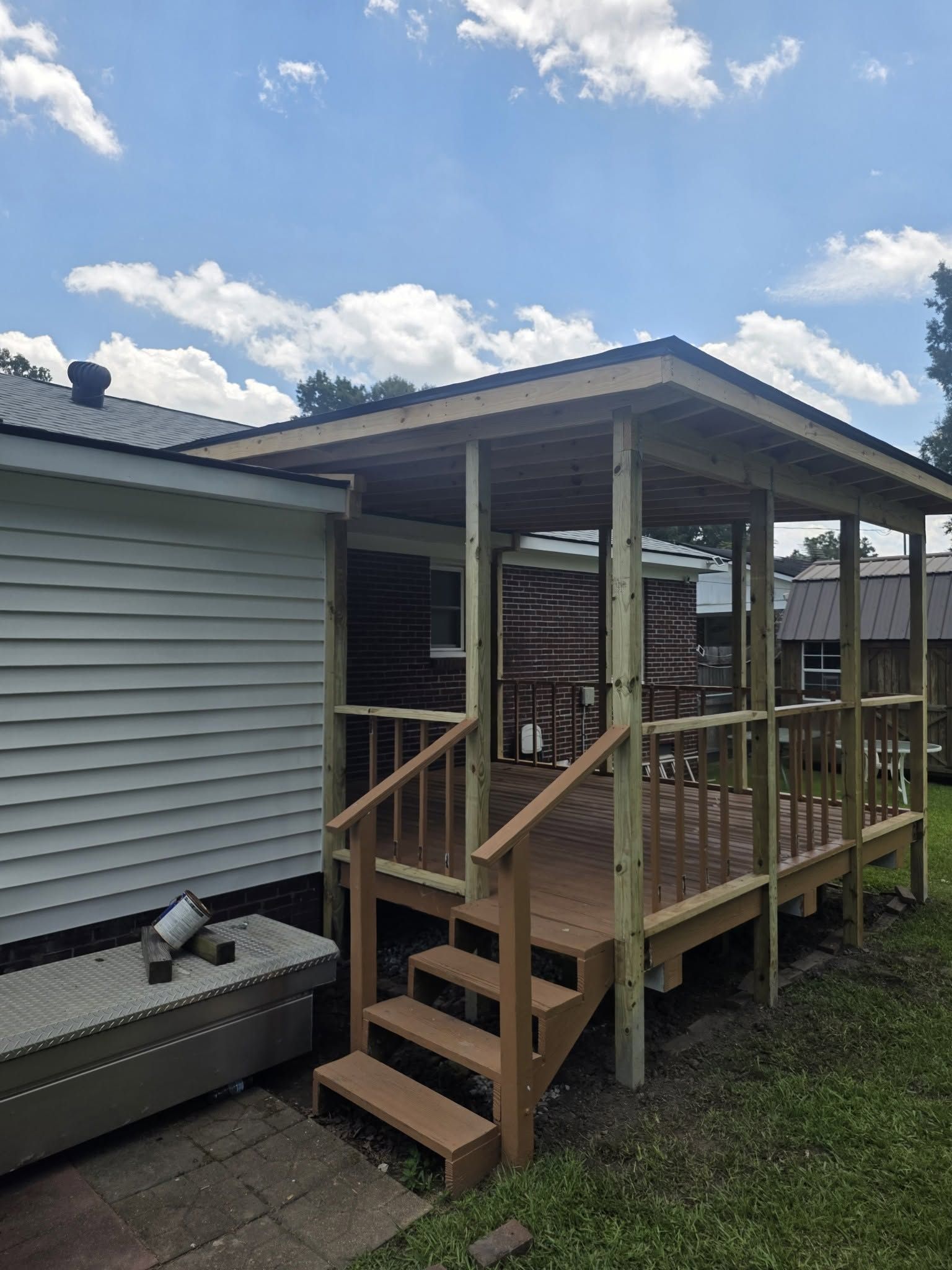 Wooden porch ramp and steps attached to a house exterior under a covered roof