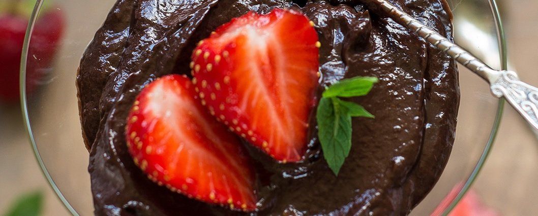 Chocolate dessert in a glass, topped with fresh strawberries and mint.