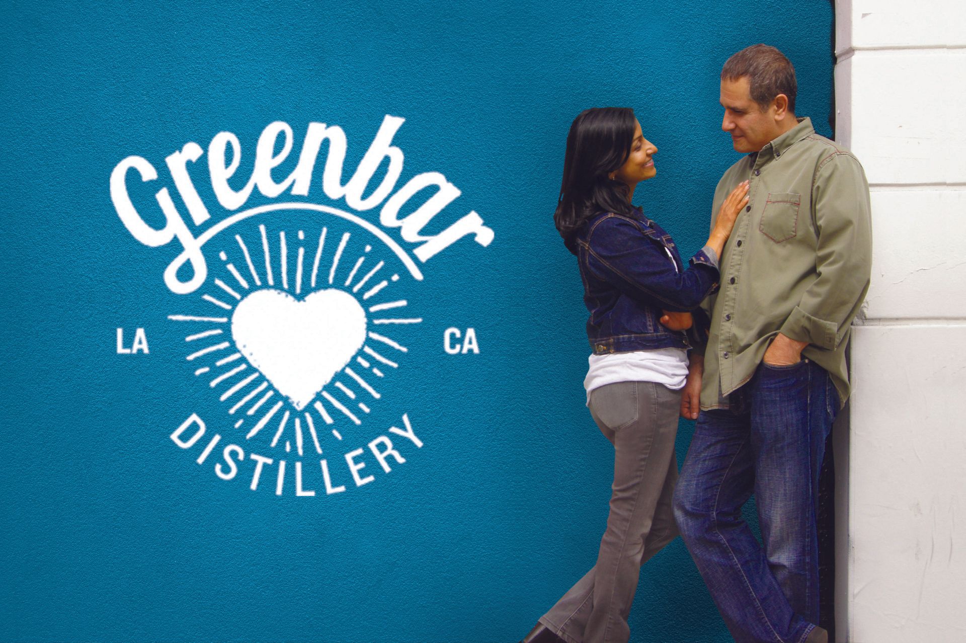 Couple leans against a blue wall with the 