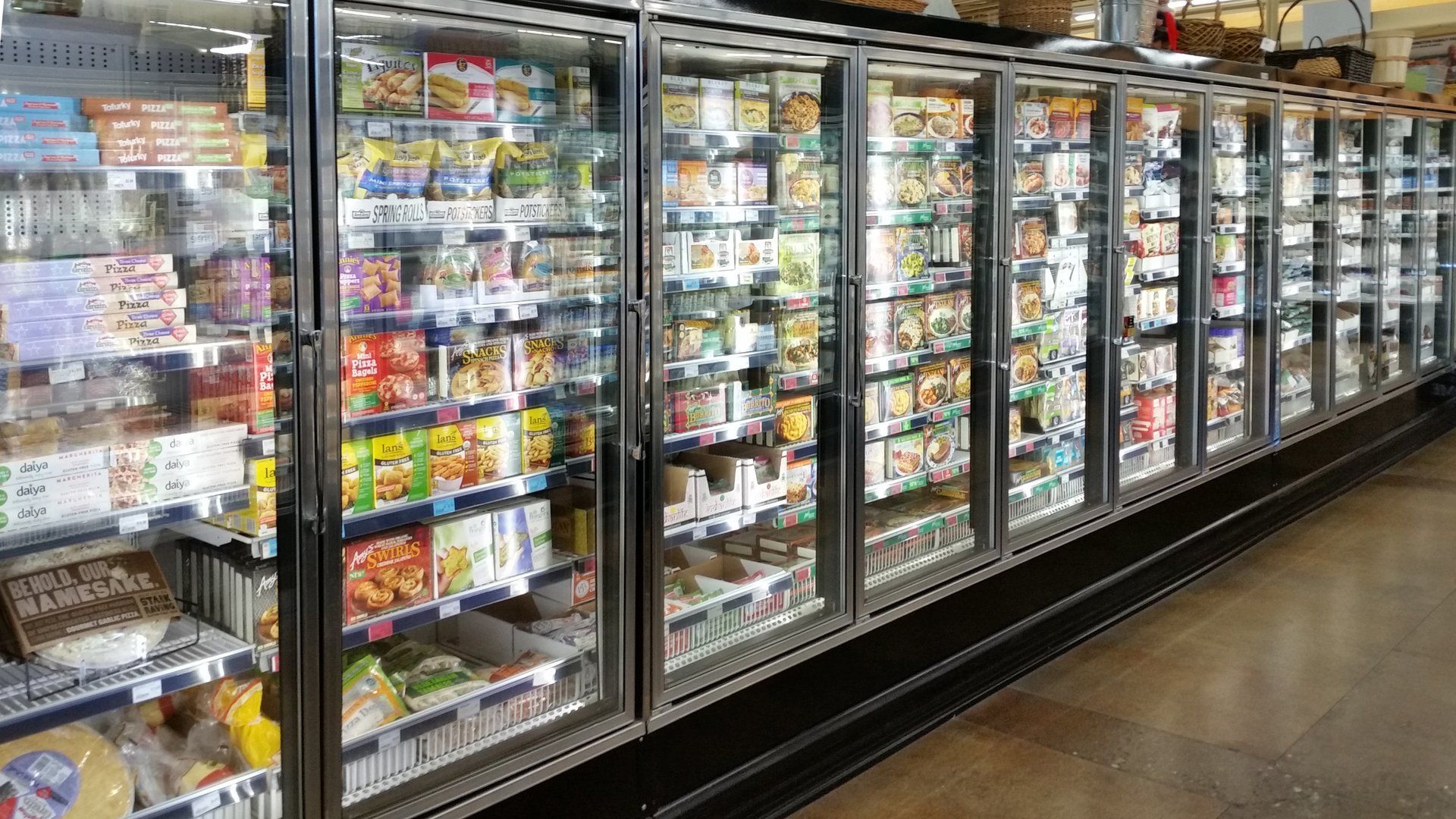 Refrigerated freezer doors in a supermarket, filled with various frozen food products.