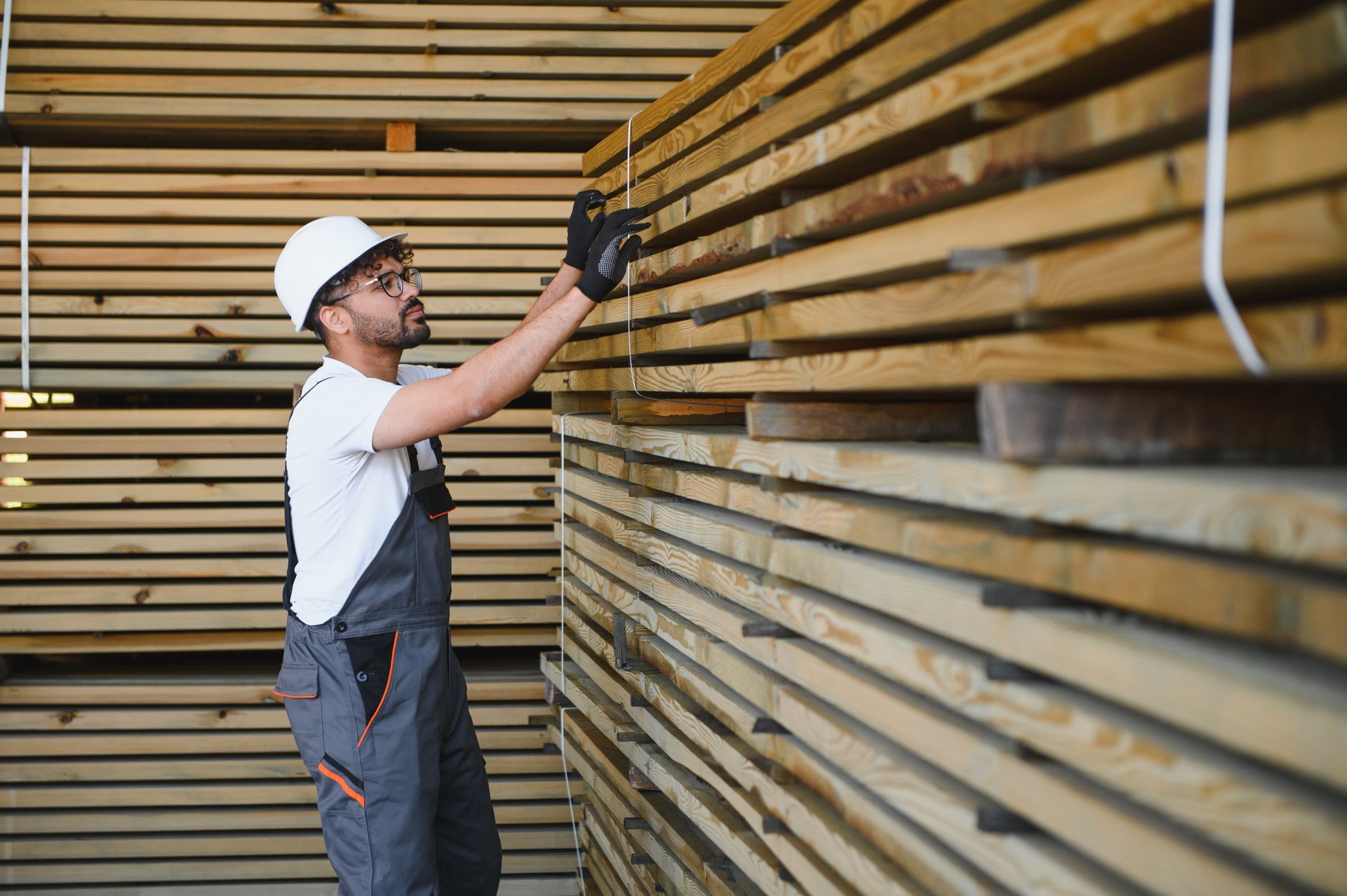 A carpenter is inspecting wooden planks in a timber warehouse.