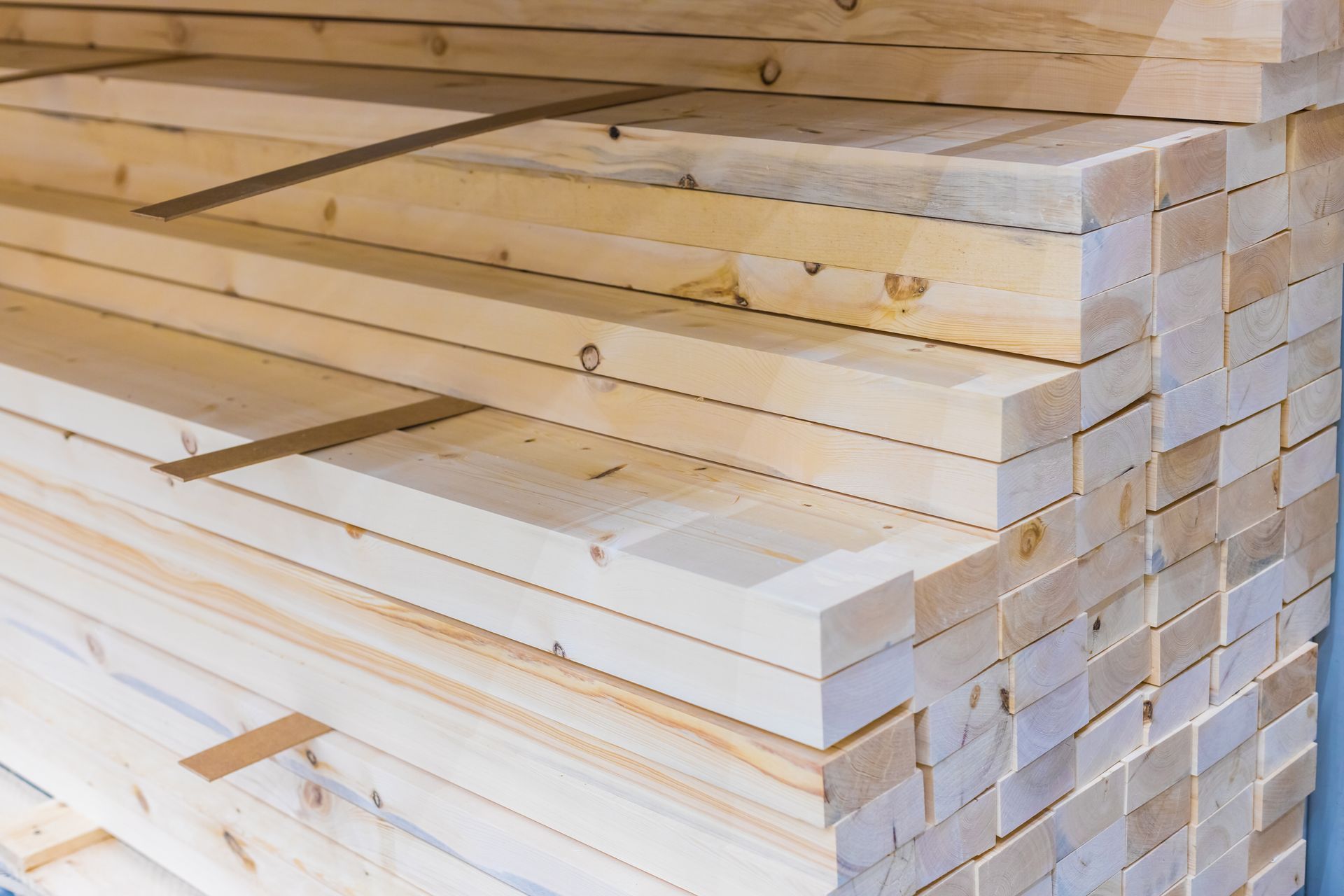 Person kneels to drill timber decking outside house, with tools and greenery in the background.