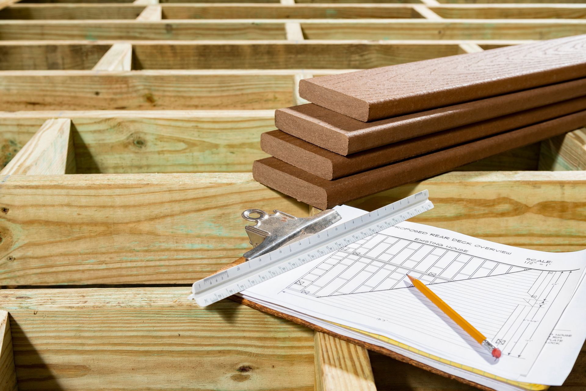 Close-up of a clipboard, on top of a wooden structure and next to composite decking materials.