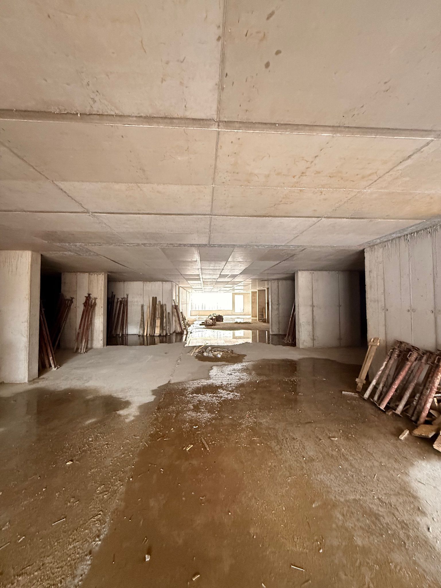 Galleria di cemento allagata, piena d'acqua e detriti; in fondo si intravede la luce del giorno.