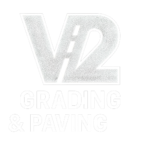 V2 Grading & Paving logo, white text on a white background. Features the letters V2 with a road graphic between them.