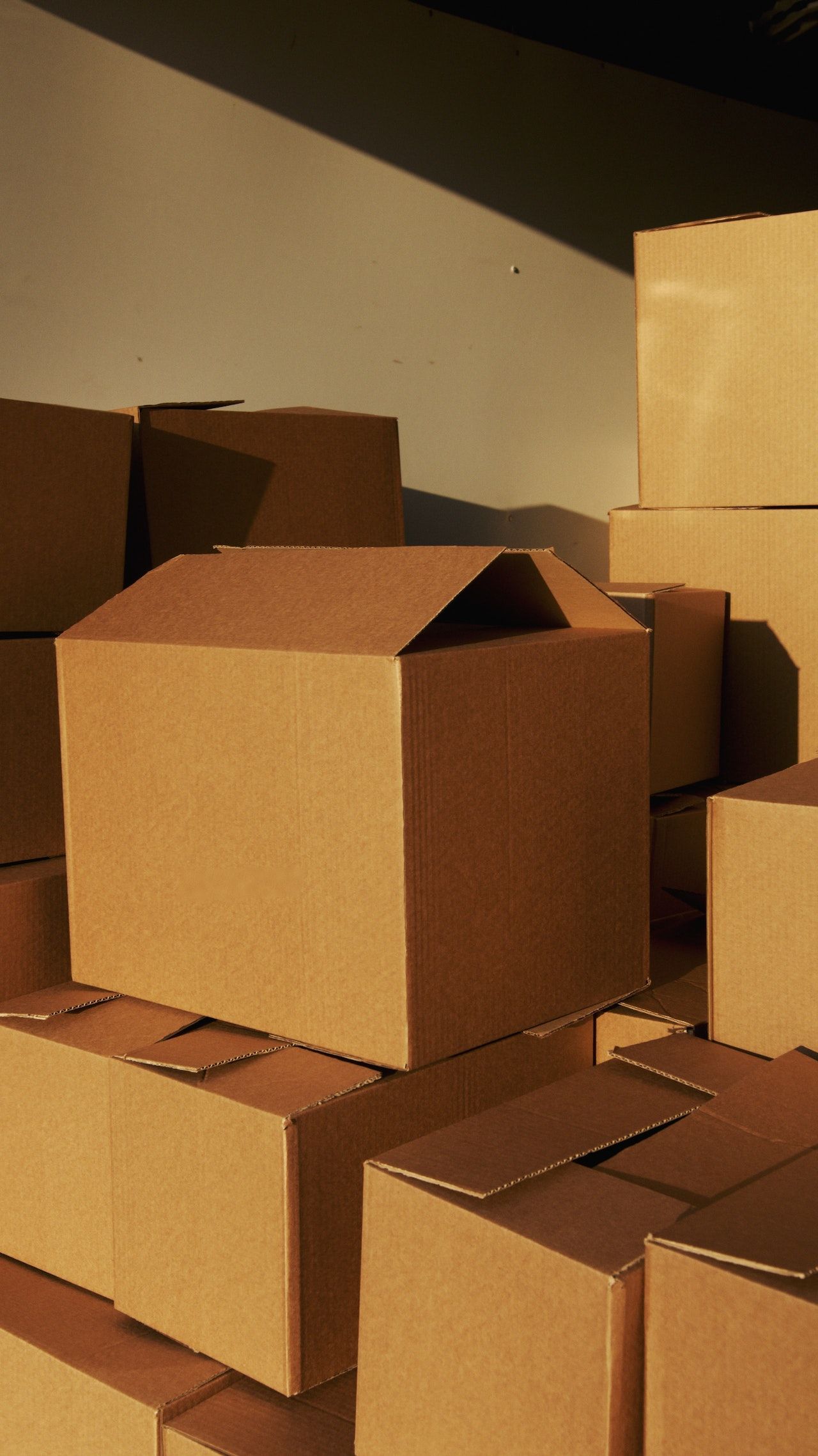 Packed moving truck with stacked boxes, wrapped furniture, and loose items inside an empty cargo bay