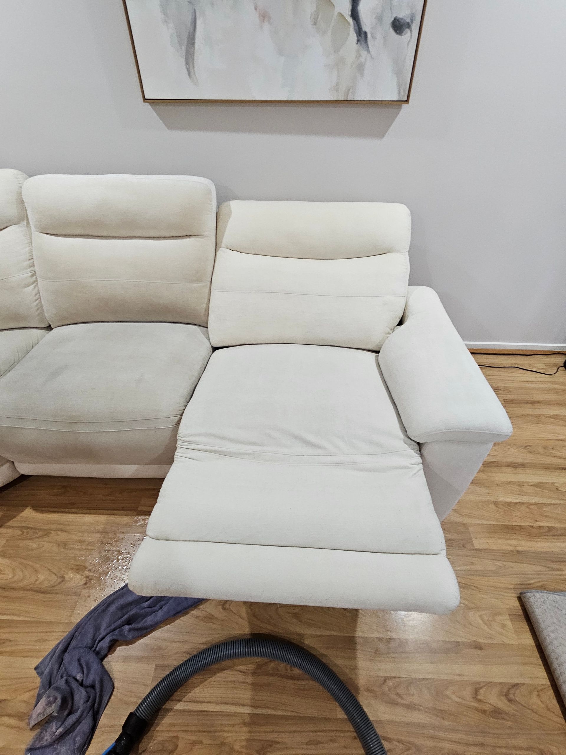 A white couch is sitting on a wooden floor next to a vacuum cleaner. — Pinnacle Carpet & Upholstery Cleaning In Lake Macquarie, NSW