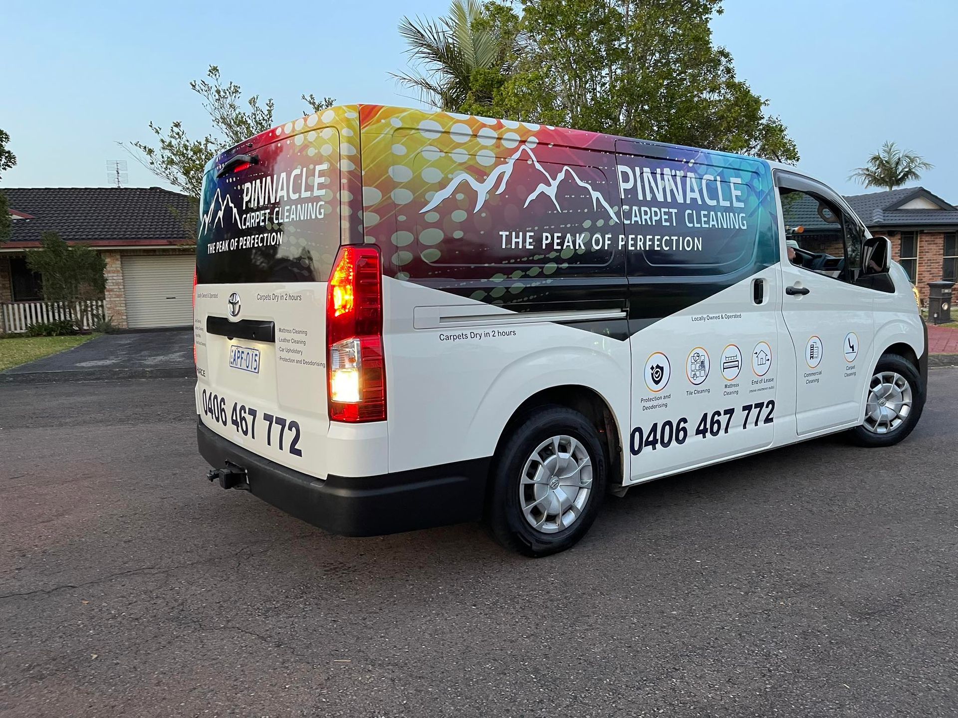 A White Van With A Colourful Wrap Is Parked In Front Of A House — Pinnacle Carpet & Upholstery Cleaning In Wyong, NSW
