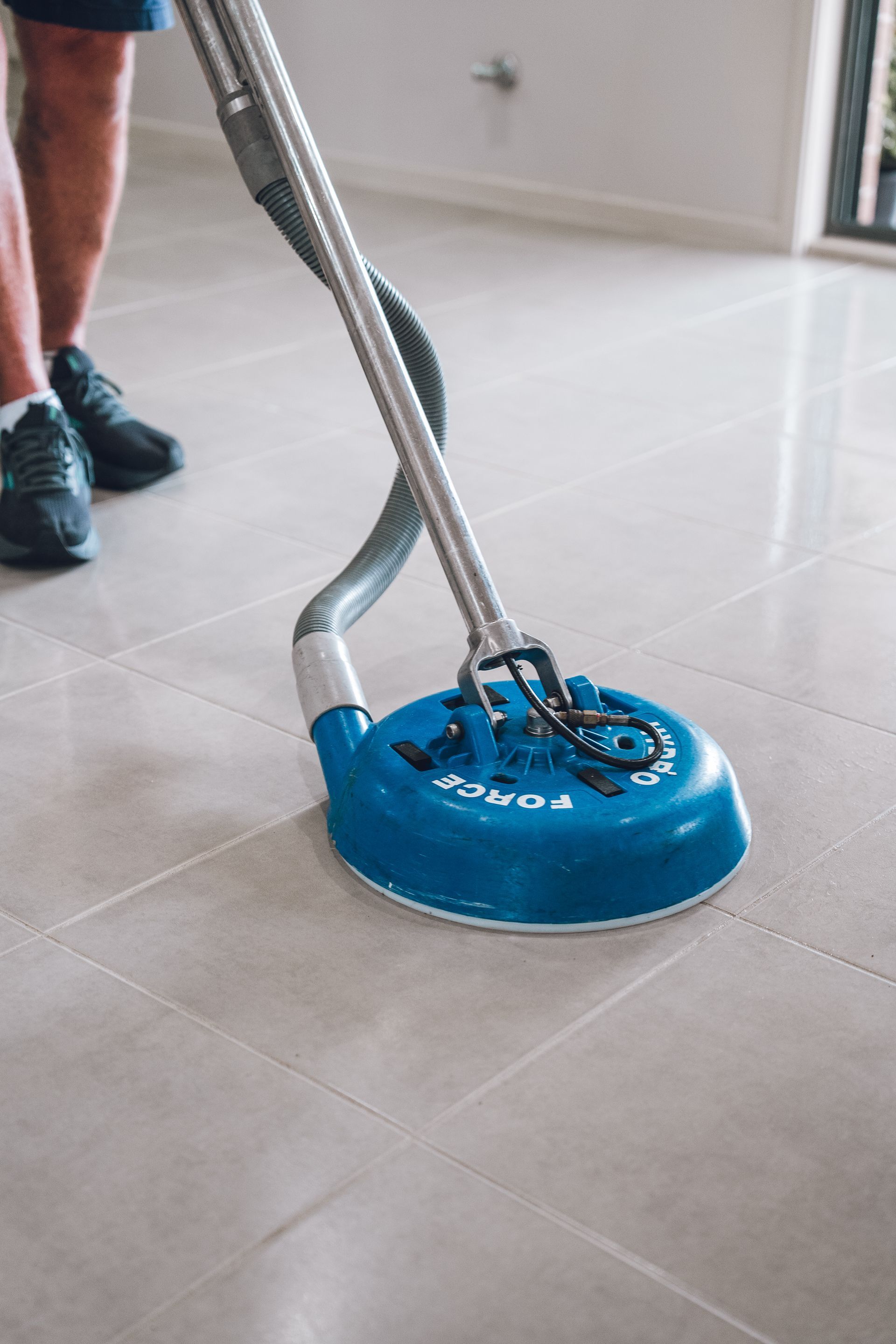 A person is cleaning a tiled floor with a vacuum cleaner. — Pinnacle Carpet & Upholstery Cleaning In Lake Macquarie, NSW