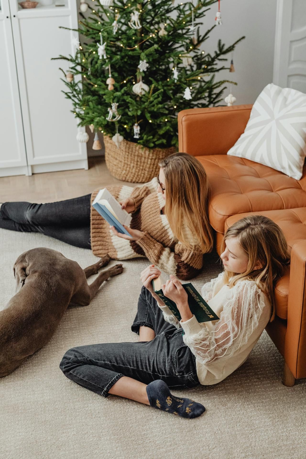 A woman and a girl are sitting on the floor reading a book. — Pinnacle Carpet & Upholstery Cleaning In Wyong, NSW