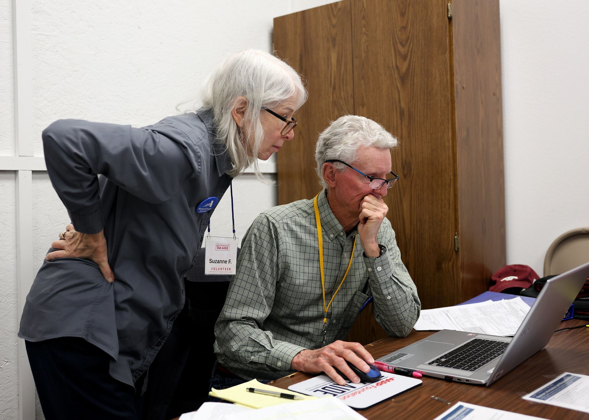 Two volunteers looking at a document on a laptop screen
