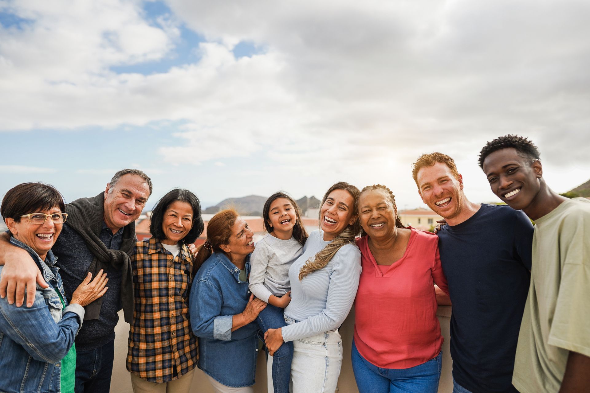 Group of smiling people against a cloudy sky