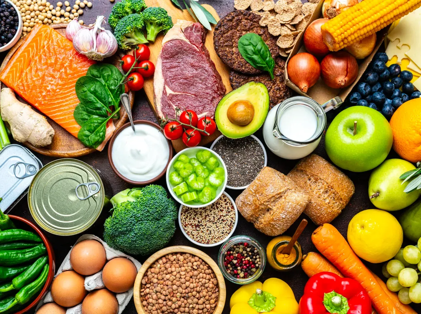 Spread of various foods including grains, nuts, salmon, veggies, apples, steak, etc